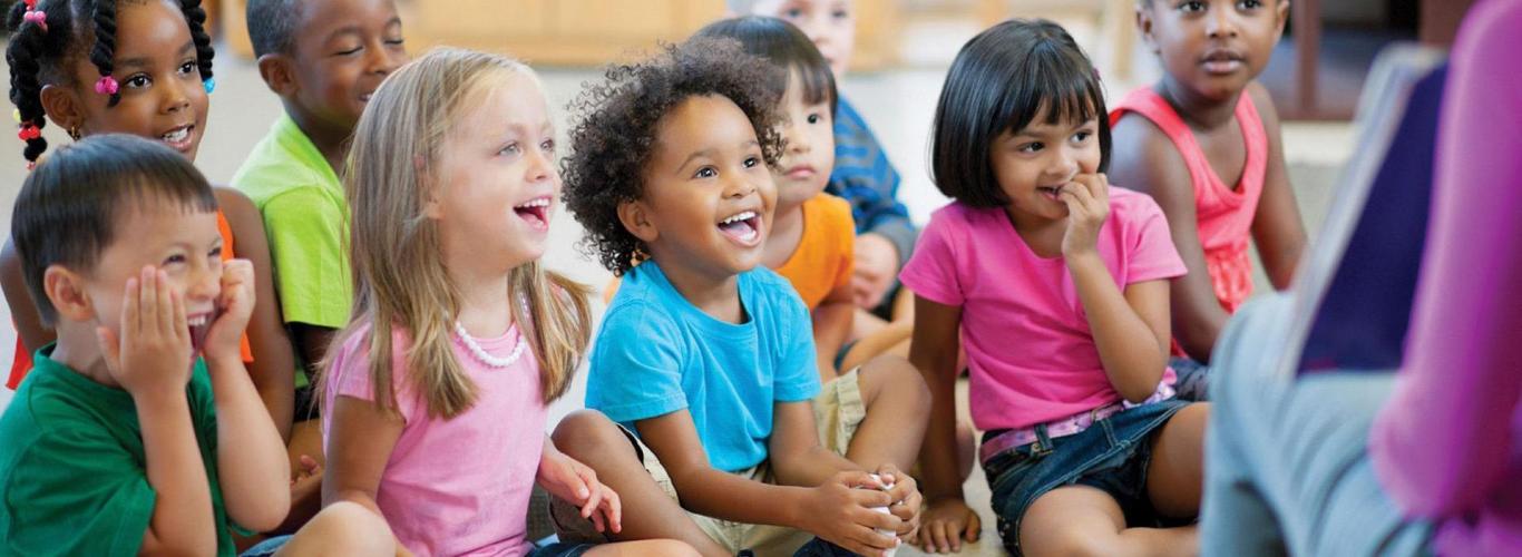 Pre-K class listening to teacher read a book